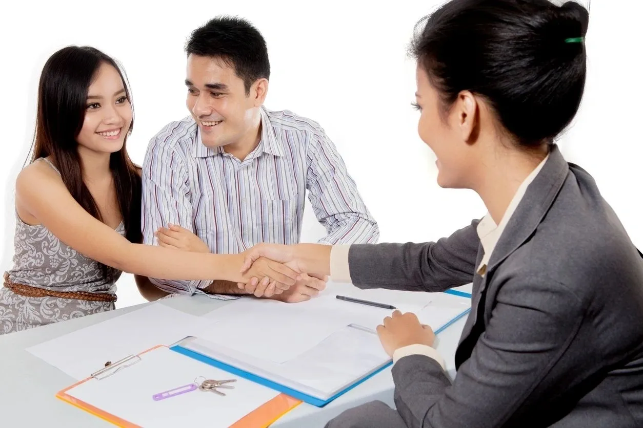 A man and woman shaking hands over papers.